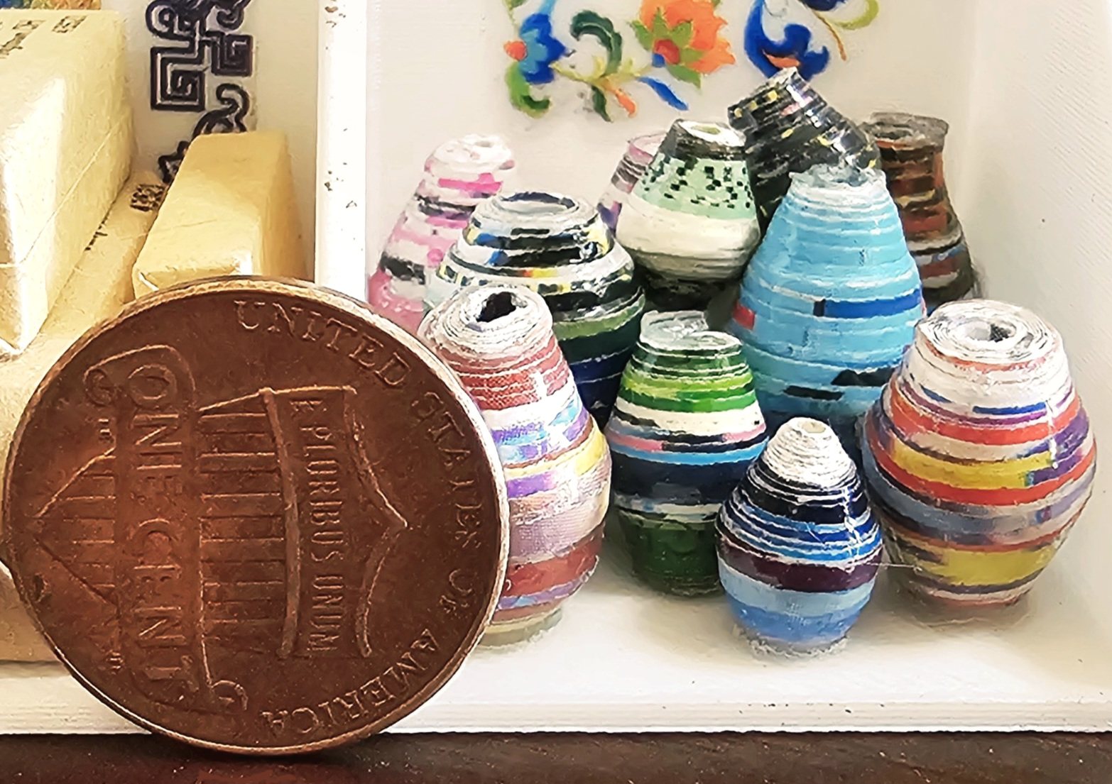 A row of handmade paper pots beside a US penny, showing just how small they are