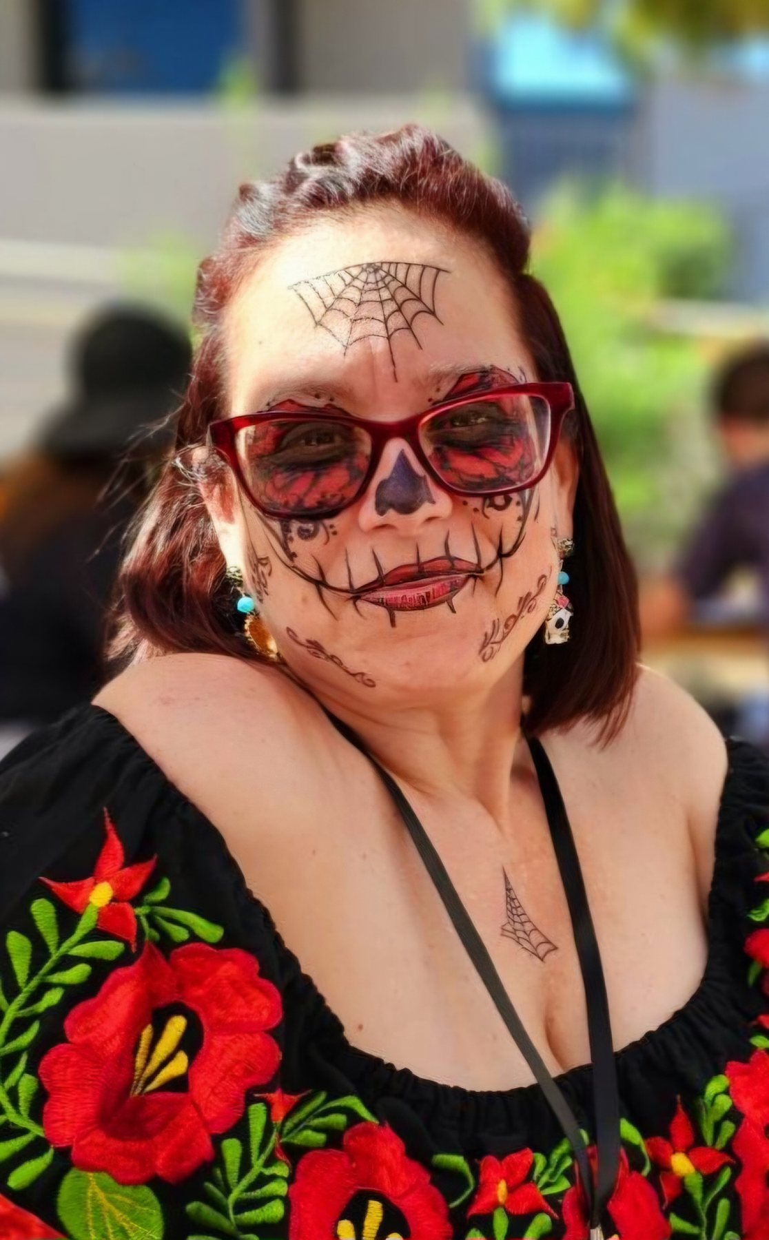 Nichole at a community art event wearing hand-painted Día de los Muertos face art